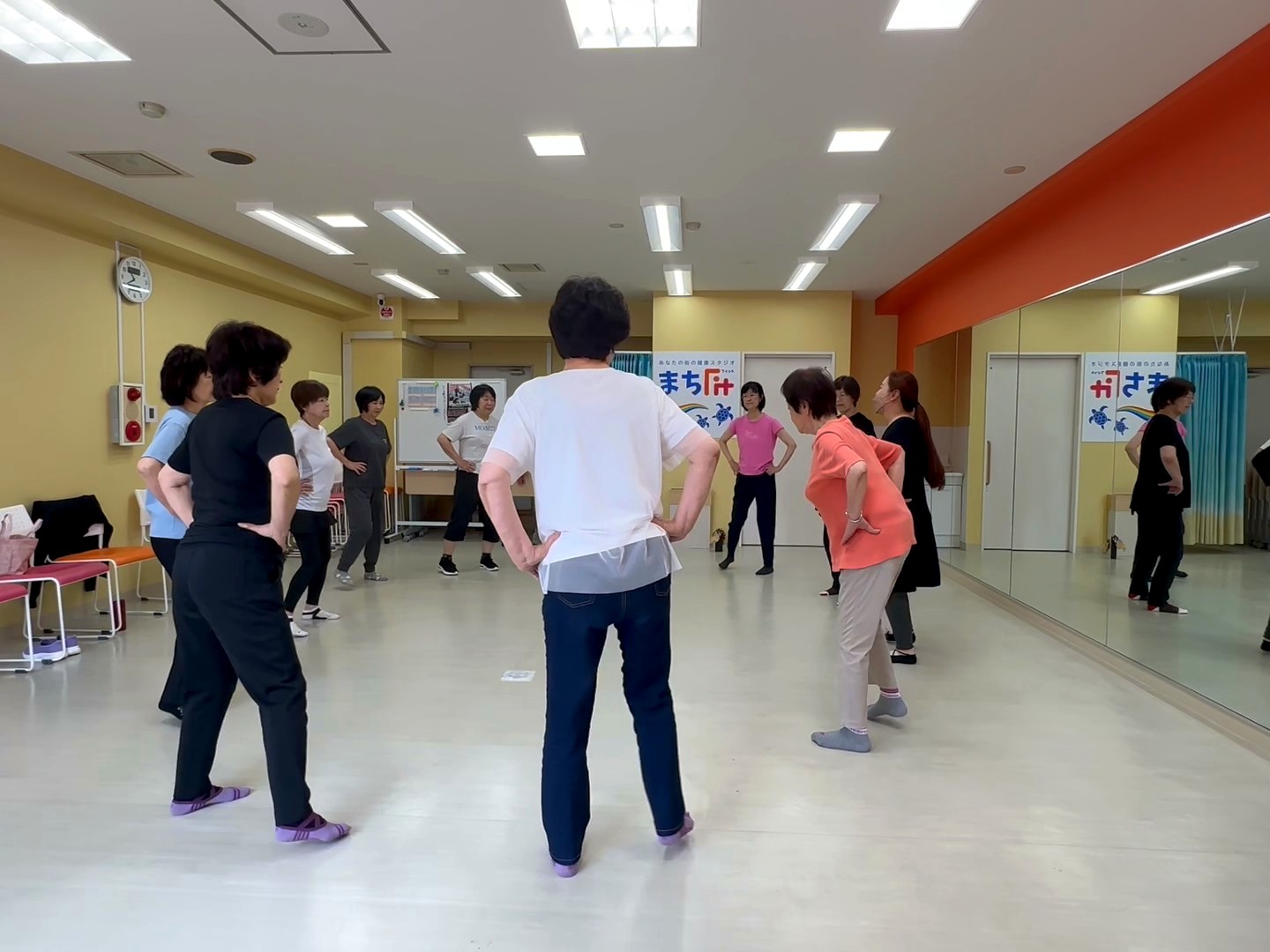 川崎スタジオで、腰に手を添えてフラの基本ステップを踏む参加者たち